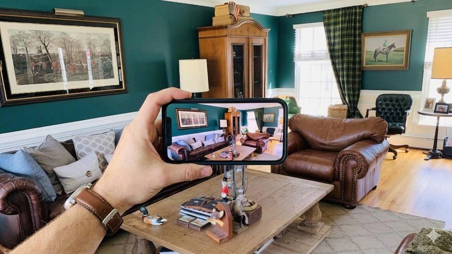 An agent photographing an occupied living room with their phone during the walkthrough