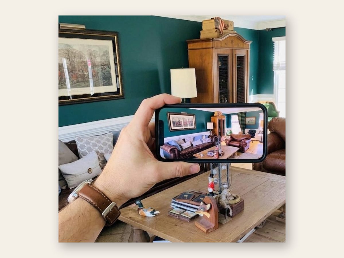 An agent photographing an occupied living room with their phone during the walkthrough